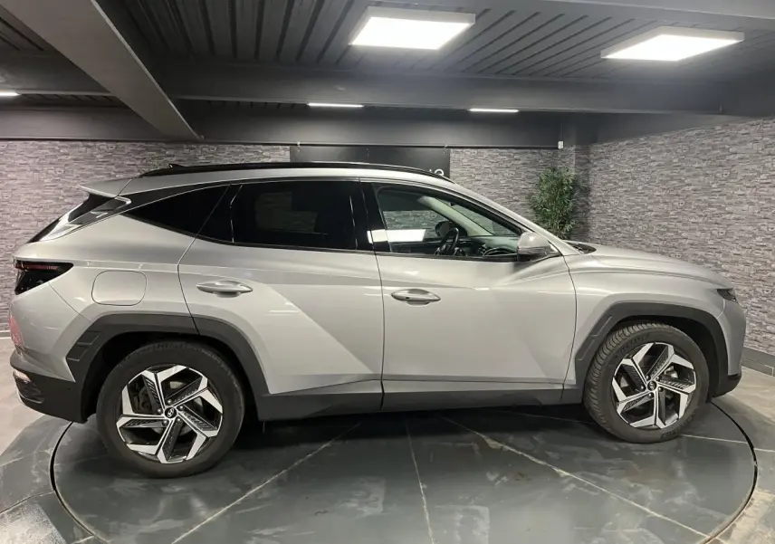 Profil côté gauche du Hyundai Tucson gris métallisé 2023 avec jantes alliage et lignes anguleuses marquées.
