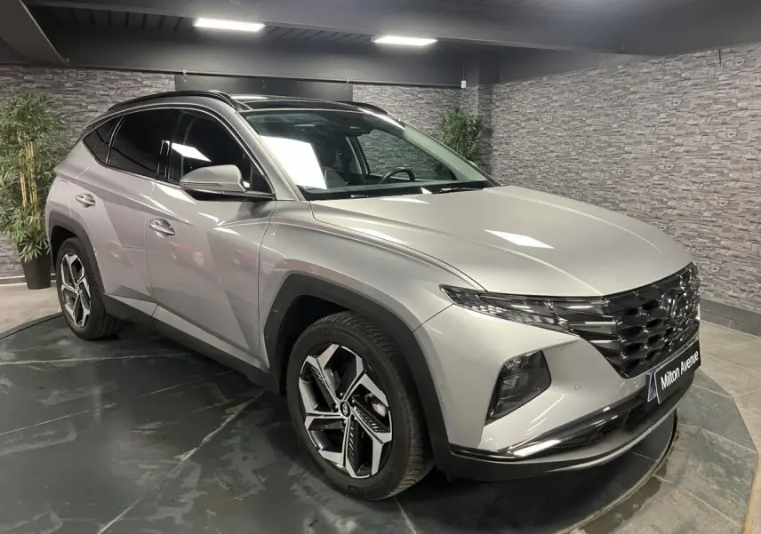 Vue 3/4 avant droite du Hyundai Tucson gris métallisé 2023 avec calandre noire et jantes alliage distinctives.