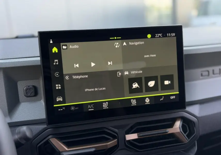 Écran tactile 10 pouces du tableau de bord du Dacia Duster 2025 avec commandes climatisation et finition brun cuivré.