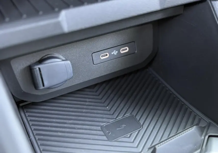 Gros plan sur la console centrale du Dacia Duster 2025, montrant les ports USB-C et le chargeur à induction noir.