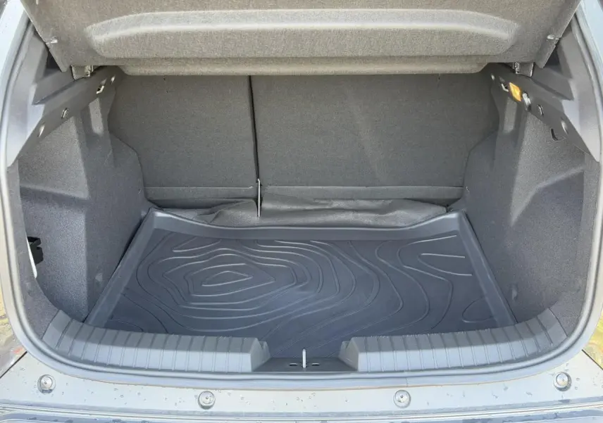 Coffre ouvert vu de l'arrière d'un Dacia Duster 2025 noir nacré avec tapis de protection en caoutchouc.