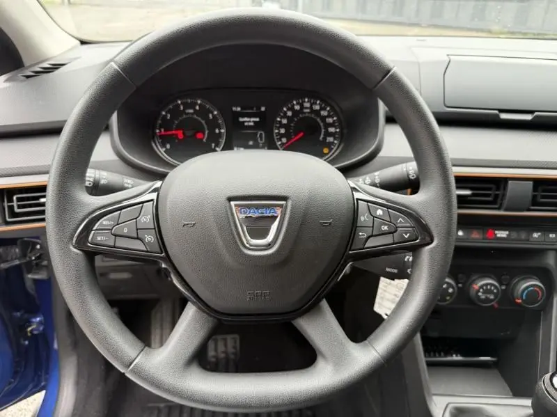 Vue intérieure centrée sur le volant du Dacia Sandero Stepway bleu métal 2022 avec commandes intégrées et tableau de bord visible.