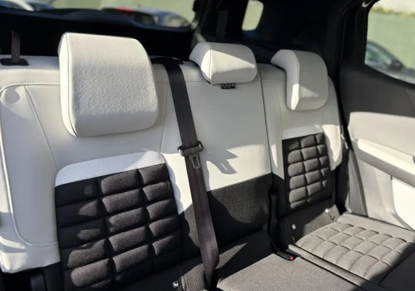 Vue rapprochée de la banquette arrière 3 places bicolore noire et blanche du Citroën C3 Aircross Hybrid 2025.