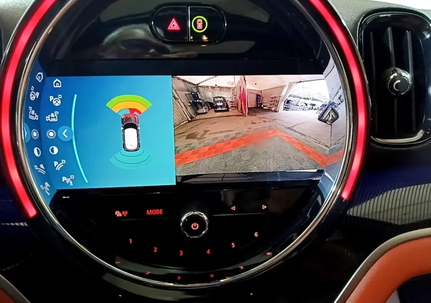 Affichage tactile circulaire du tableau de bord MINI Countryman bleu, montrant caméra de recul et capteurs de stationnement.