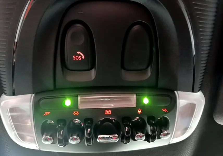 Gros plan sur les commandes de plafonnier et bouton SOS du MINI Countryman Cooper SE bleu, intérieur noir.
