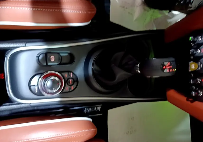 Vue plongeante sur la console centrale noire et les sièges en cuir marron du MINI Countryman Cooper SE 2021.