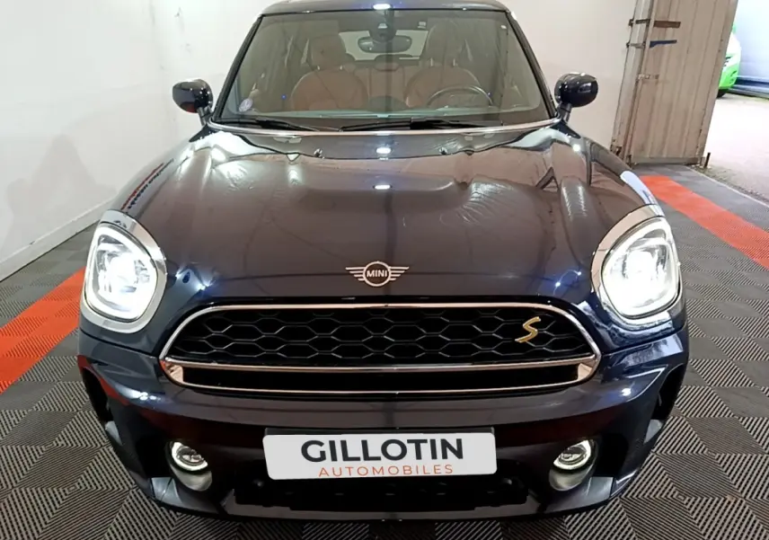 Vue frontale d'une MINI Countryman Cooper SE bleu foncé avec phares allumés et calandre distinctive "S"