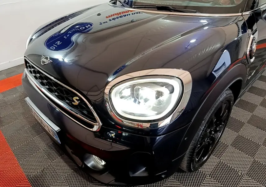 Vue 3/4 avant droit d'une MINI Countryman Cooper SE bleu foncé avec phares LED allumés et jantes noires.