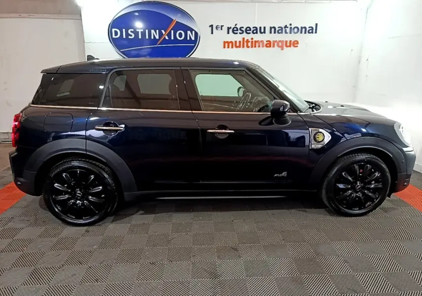 Profil droit d'une MINI Countryman Cooper SE hybride rechargeable bleu foncé avec jantes noires dans un showroom.