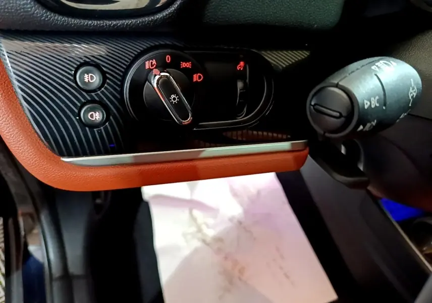 Gros plan sur la commande des phares et la manette multifonction côté gauche du tableau de bord brun et noir de la MINI Countryman.