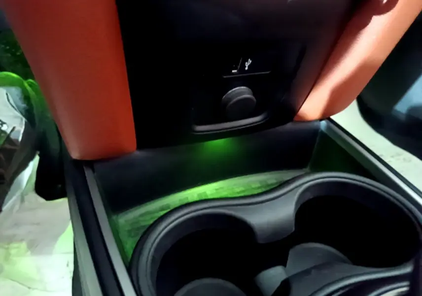 Gros plan sur la console centrale noire avec porte-gobelets et prise USB du MINI Countryman Cooper SE bleu.