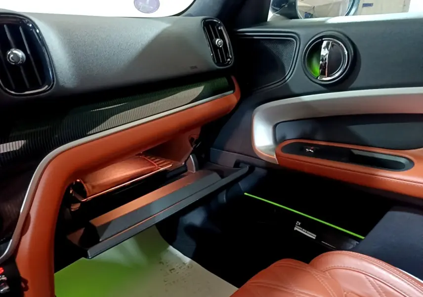 Intérieur côté passager du MINI Countryman hybride, avec garnitures cuir marron et inserts argentés sur la portière.
