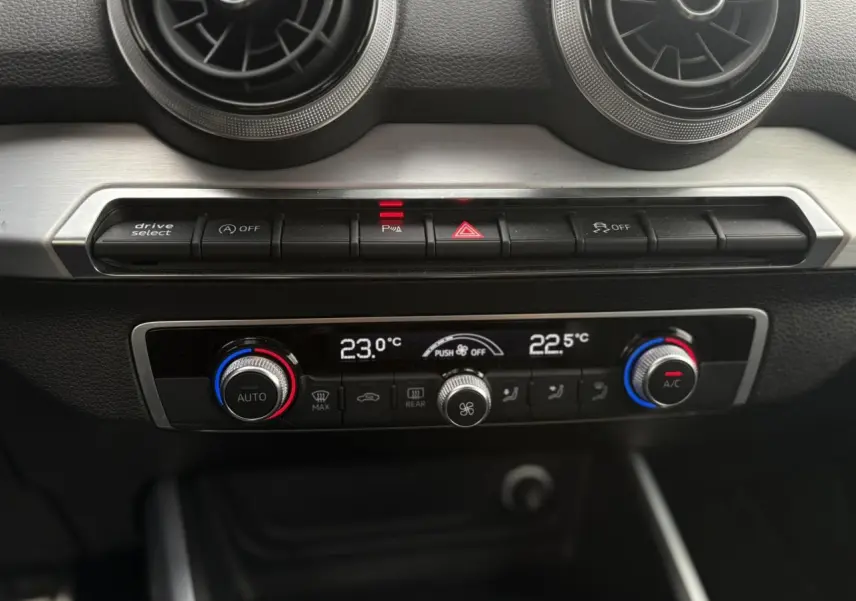 Vue rapprochée du tableau de bord de l’Audi Q2 35 TDI 150 S-Tronic S-Line, montrant la climatisation automatique bi-zone.