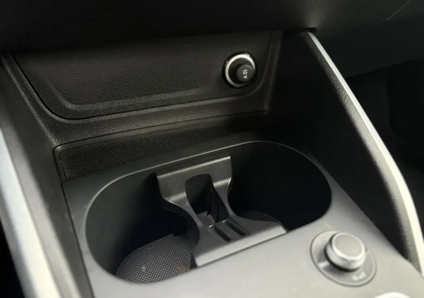 Gros plan sur le porte-gobelets central noir de l’Audi Q2 35 TDI 150 S-Tronic S-Line 2025, intérieur sombre.