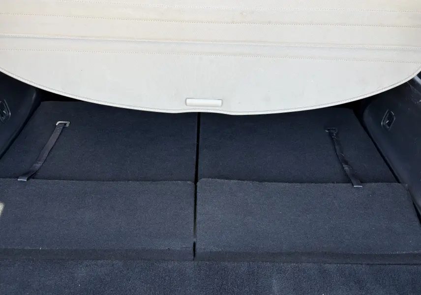 Coffre du Nissan X-TRAIL 2016 White Edition 7 places vu de l'arrière, sièges rabattus et cache-bagages beige partiellement visible.