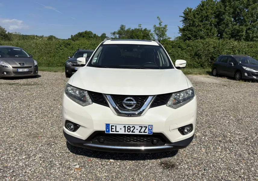 Vue de face d'un Nissan X-Trail blanc 2016, version White Edition, sur un parking extérieur sous un ciel bleu.