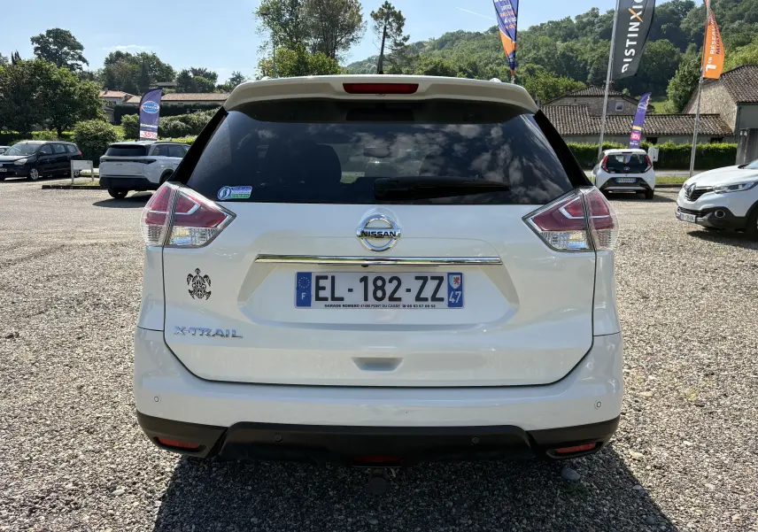 Vue arrière d'un Nissan X-TRAIL blanc 2016 avec logo X-TRAIL et plaque d'immatriculation française visible.