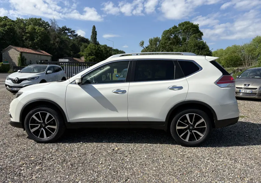 Vue de profil côté gauche d'un Nissan X-Trail 2016 blanc, version White Edition 7 places avec jantes alliage noires.
