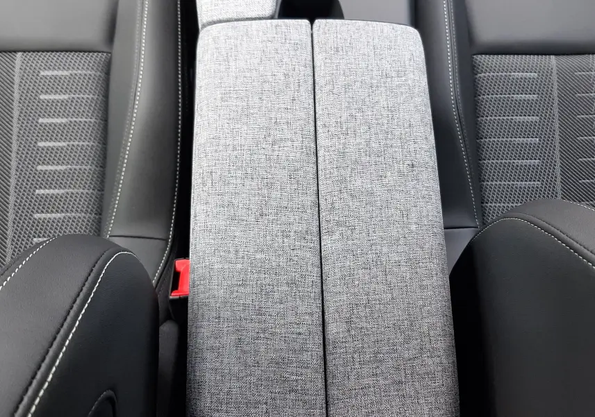 Vue plongeante sur l'accoudoir central gris clair et les sièges noirs en tissu et cuir du Peugeot 3008 Hybrid 2026.