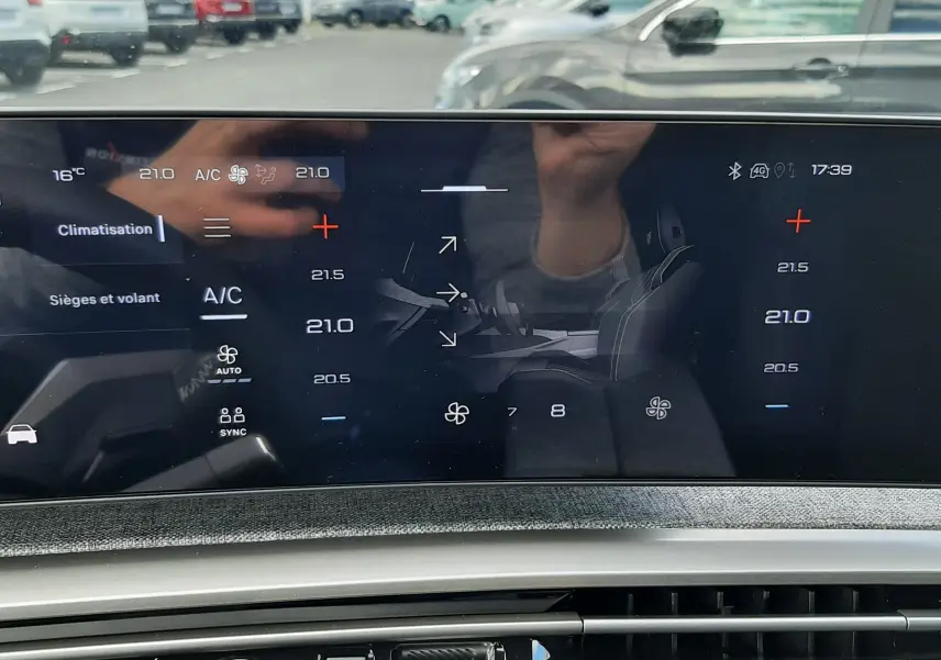 Vue intérieure sur l’écran tactile de climatisation du Peugeot 3008 gris titane, avec bouton start/stop et commandes modernes.