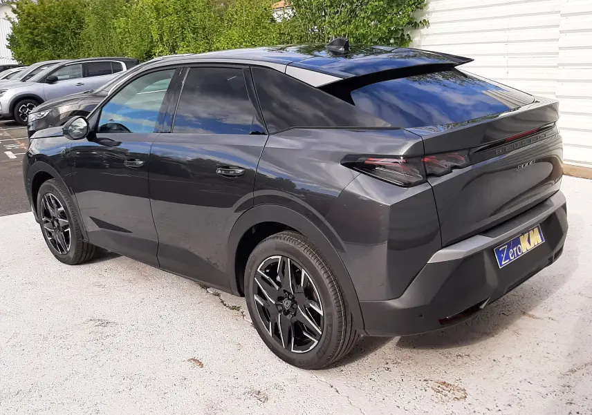 Vue 3/4 arrière droite d'un Peugeot 3008 gris titane 2026 avec vitres teintées et jantes noires distinctives.