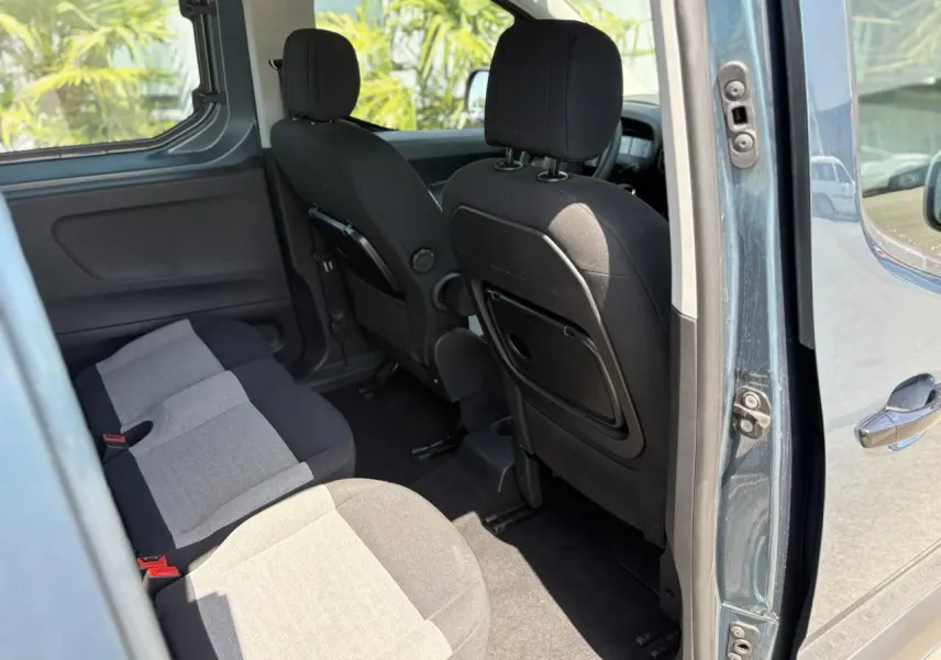 Vue intérieure côté droit du Citroën Berlingo ë-136 54kWh bleu Kiama, montrant les sièges arrière et banquette rabattable.