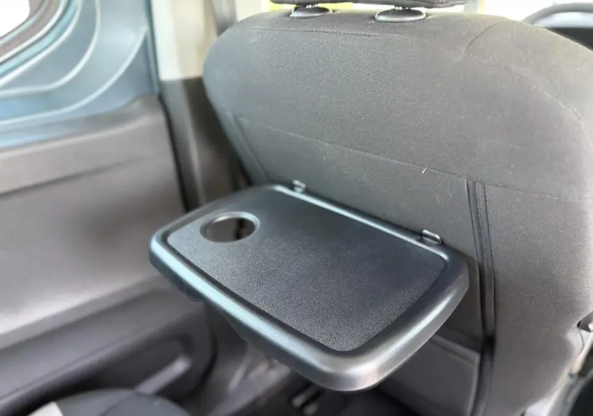 Détail de la tablette aviation rabattable noire sur le dossier du siège avant du Citroën Berlingo ë-136 Bleu Kiama.