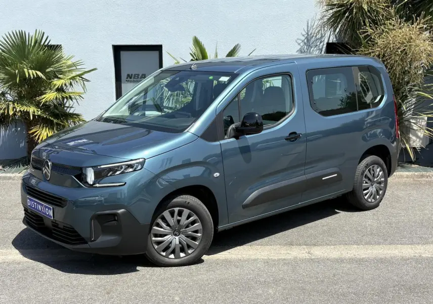 Vue 3/4 avant droit du Citroën Berlingo ë-136 54kWh bleu Kiama avec jantes tôles et porte coulissante droite visible.