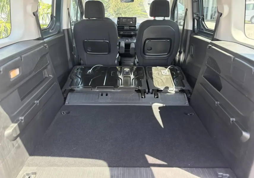 Vue intérieure arrière du Citroën Berlingo ë-136 avec banquette rabattue et plancher de coffre plat, ambiance Urban Grey.