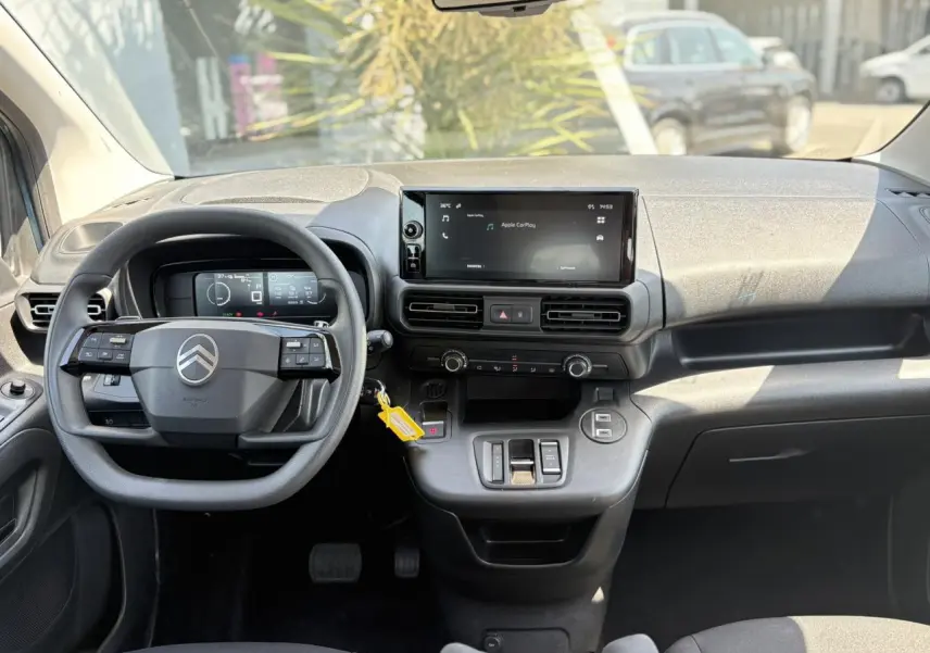 Vue intérieure frontale du tableau de bord du Citroën Berlingo ë-136, avec écran tactile et volant multifonction.