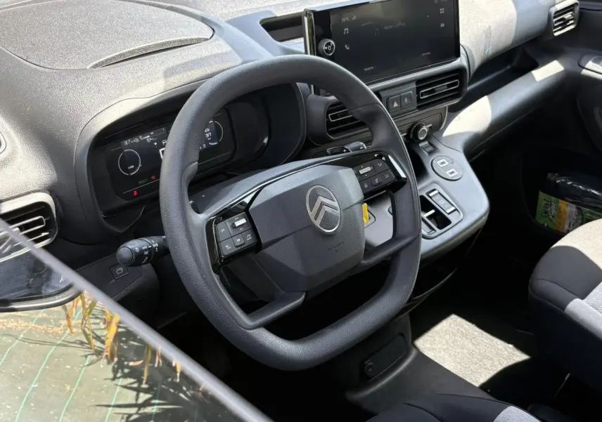 Vue intérieure du poste de conduite du Citroën Berlingo ë-136 2025, volant multifonction et écran tactile 10 pouces.