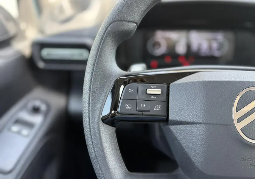 Gros plan sur le volant multifonction gris du Citroën Berlingo 2025, avec commandes de régulateur et limiteur.