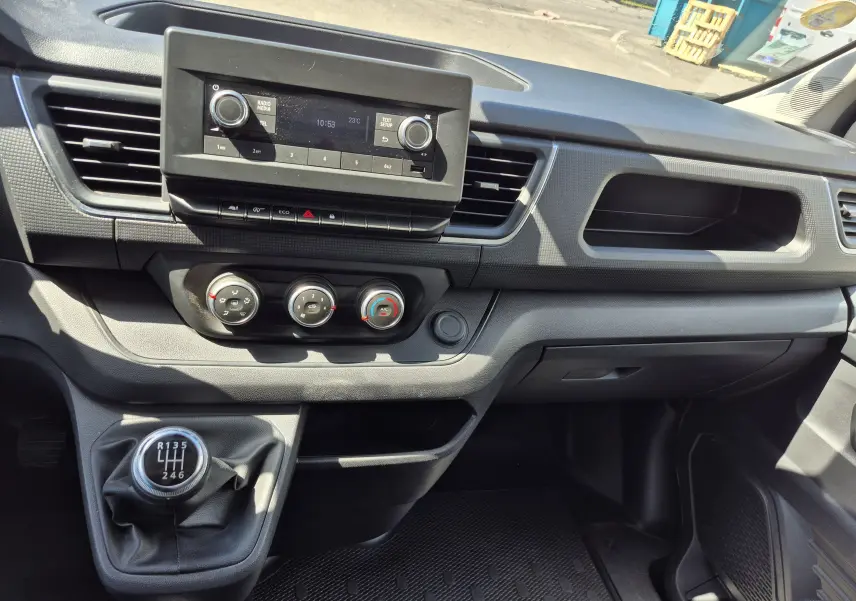 Vue intérieure du tableau de bord du Nissan Primastar blanc, avec console centrale et levier de vitesses manuel en évidence.