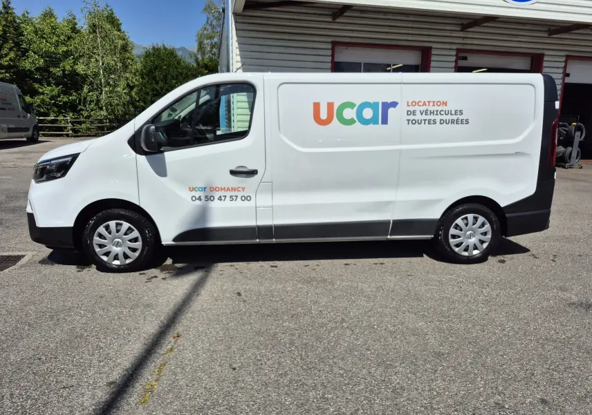 Vue de profil côté gauche d’un utilitaire Nissan Primastar blanc avec logo coloré ucar et texte de location sur la porte latérale.