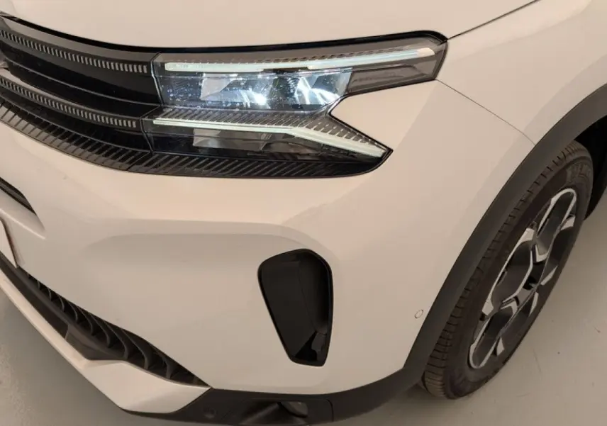 Gros plan sur l'avant droit blanc Okenite du Citroën C5 Aircross 2025 avec phares LED et jante alliage distinctive.