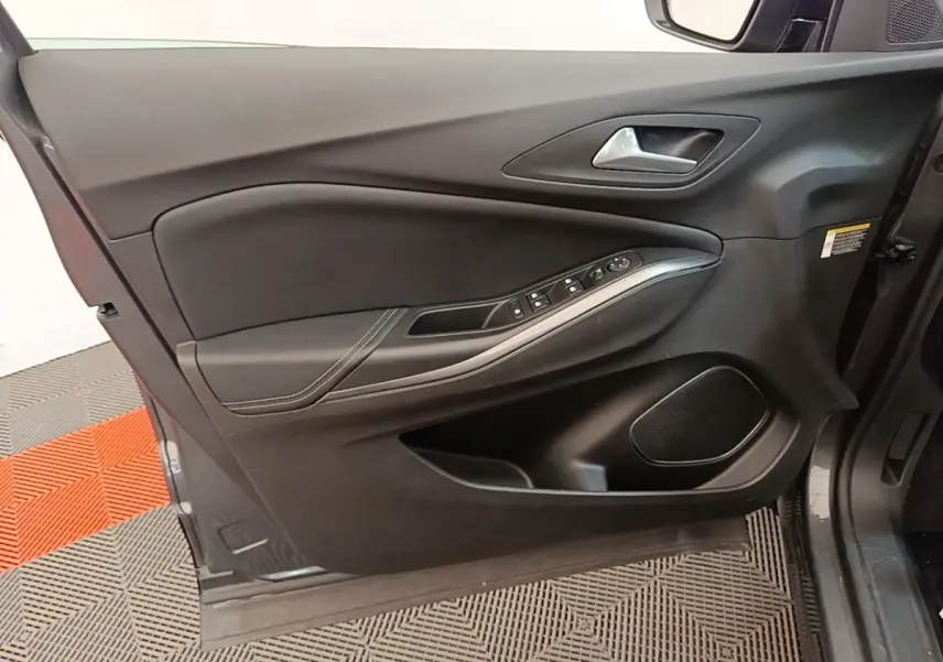Vue intérieure côté gauche de la porte avant d’un Opel Grandland X gris foncé avec commandes électriques et haut-parleur intégré.
