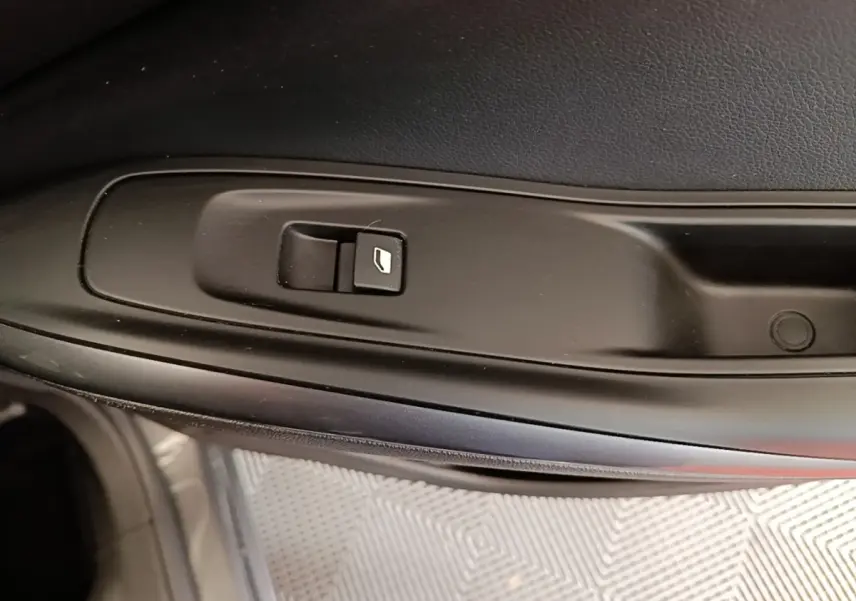 Gros plan sur le bouton de lève-vitre électrique côté conducteur de l’Opel Grandland X gris foncé.