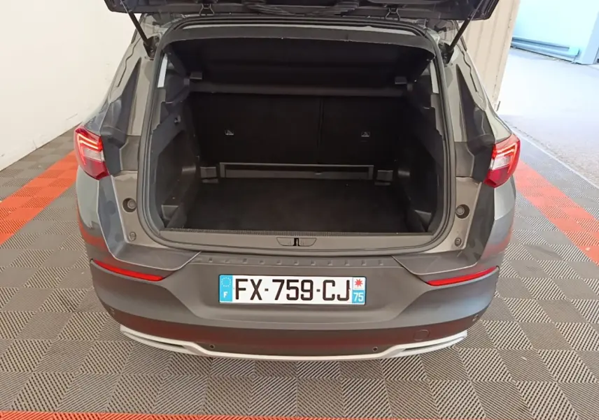 Vue arrière d'un Opel Grandland X gris foncé avec coffre ouvert, montrant l'espace de chargement vide.