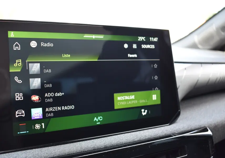 Écran tactile du système audio de la Renault Clio VI gris schiste, affichant les stations radio DAB et la chanson Nostalgie.