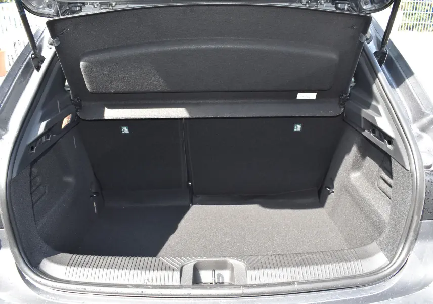 Coffre ouvert vu de l'arrière d'une Renault Clio VI gris schiste, montrant le cache-bagages rigide et l'espace de chargement.