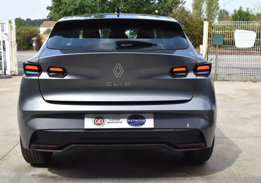 Vue arrière d'une Renault Clio VI gris schiste avec feux LED distinctifs et spoiler de toit visible.