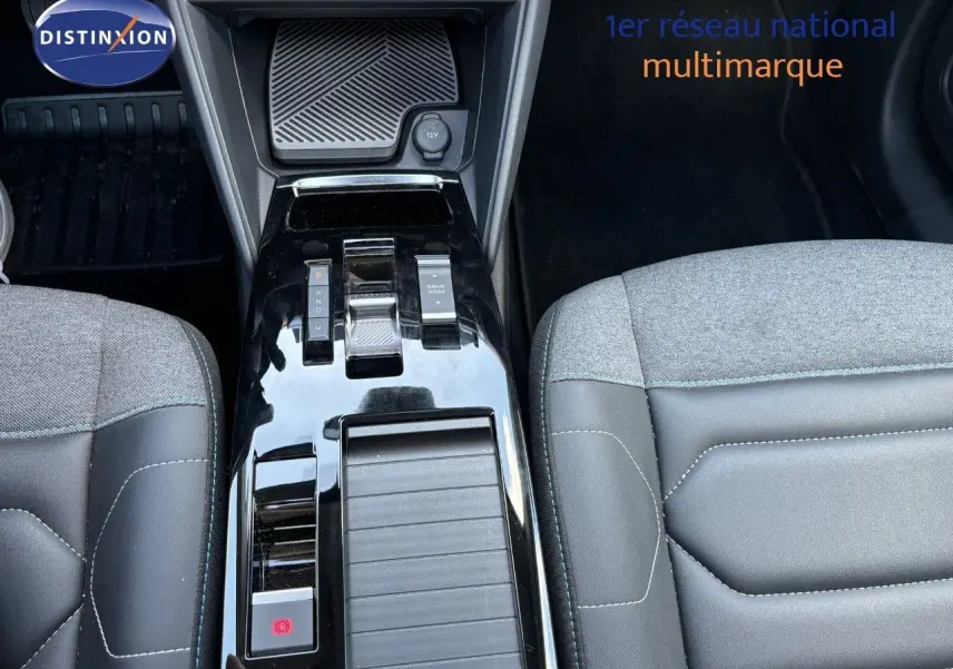 Vue rapprochée de la console centrale noire brillante et des sièges gris clair et noir du Citroën C4 Shine 2022.