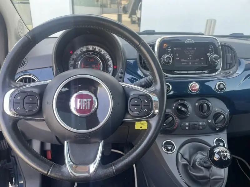 Vue intérieure du tableau de bord bleu foncé métallisé d'une Fiat 500 2016 avec volant multifonction et levier de vitesse manuel.
