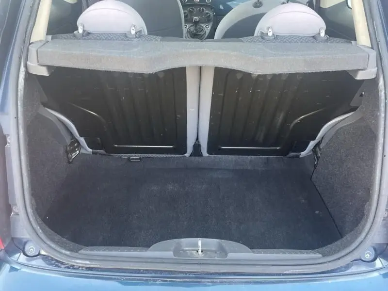 Coffre ouvert d'une Fiat 500 bleu foncé métal, vue arrière montrant l'espace de chargement et les dossiers arrière.