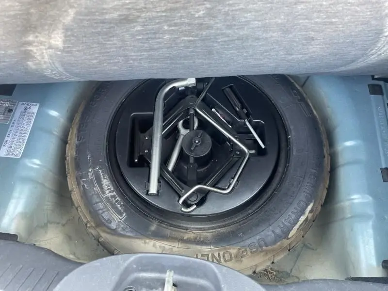 Roue de secours avec outils de changement dans le coffre d'une FIAT 500 bleu foncé métal de 2016.