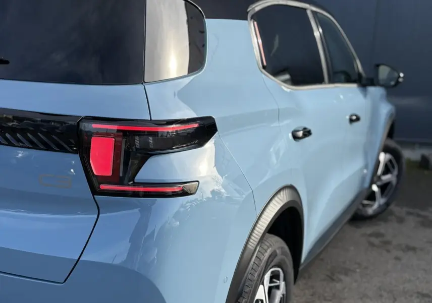 Vue 3/4 arrière droite d'une Citroën C3 Aircross 2025 bleu Monte Carlo avec toit noir et feux arrière LED distinctifs.