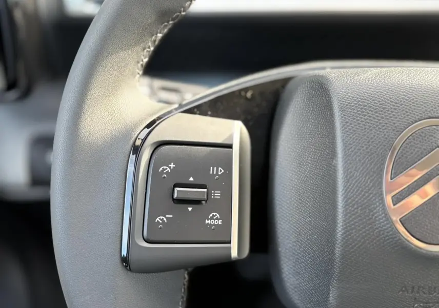 Gros plan sur les commandes au volant à gauche du Citroën C3 Aircross Hybrid 2025 avec logo et finition noire.