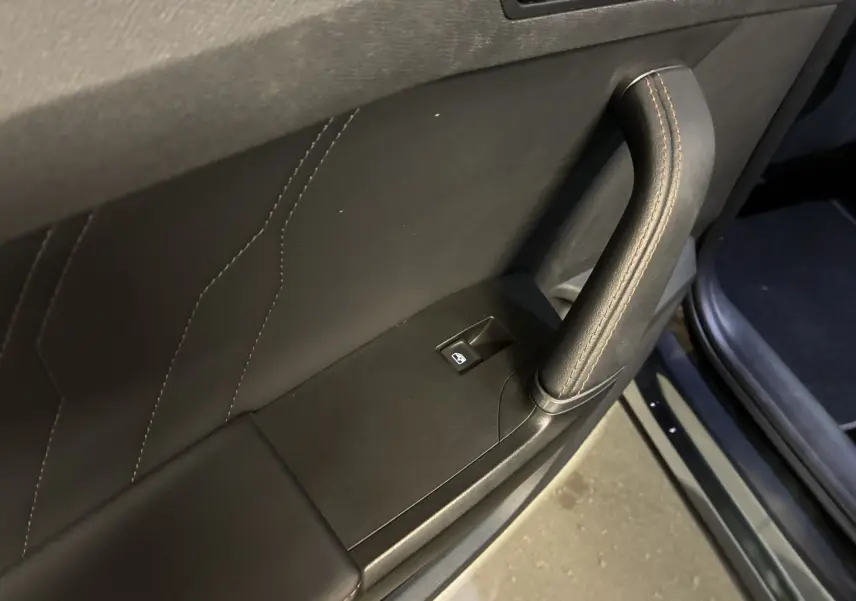 Gros plan sur la poignée de porte intérieure en cuir noir avec surpiqûres et bouton de commande de vitre du CUPRA Formentor 2023.