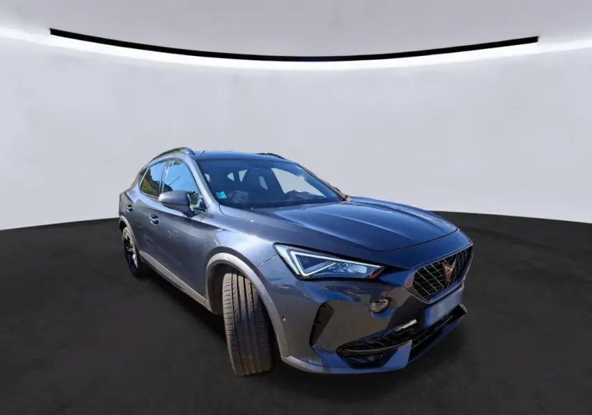 Vue 3/4 avant droit d'une CUPRA Formentor gris métallisé avec phares LED et calandre distinctive en losange.