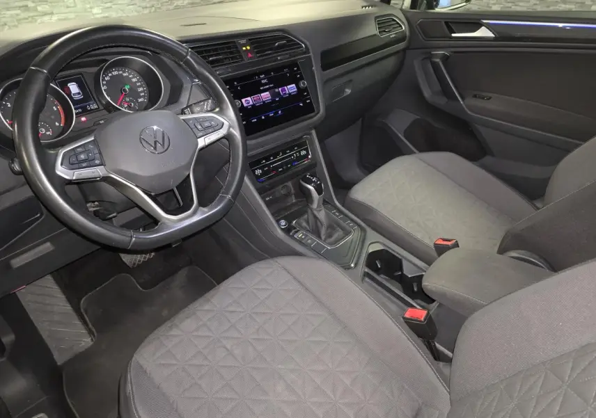 Vue intérieure avant droite du Volkswagen Tiguan 2022, sièges tissu gris et tableau de bord avec écran tactile.